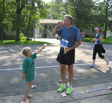 David Stowman at Dick Beardsley Half Marathon Getting Water from his Grandaughter